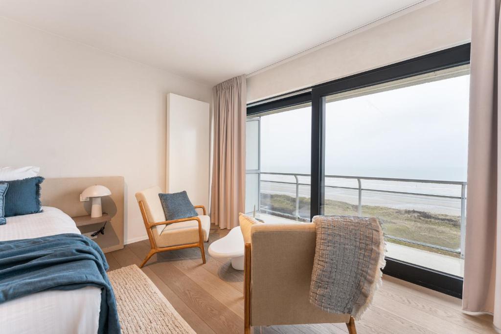 ein Schlafzimmer mit einem Bett und einem großen Fenster in der Unterkunft Seaflower - Romantische luxe studio met zeezicht in De Panne