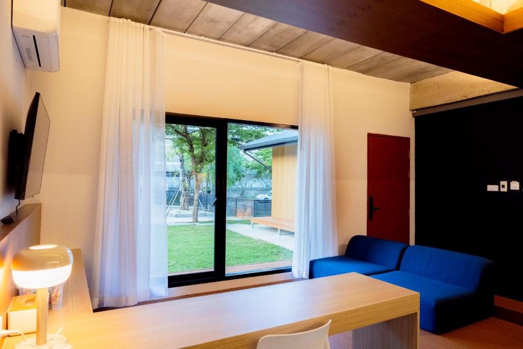 a living room with a blue couch and a large window at Karpenter Lampang in Lampang