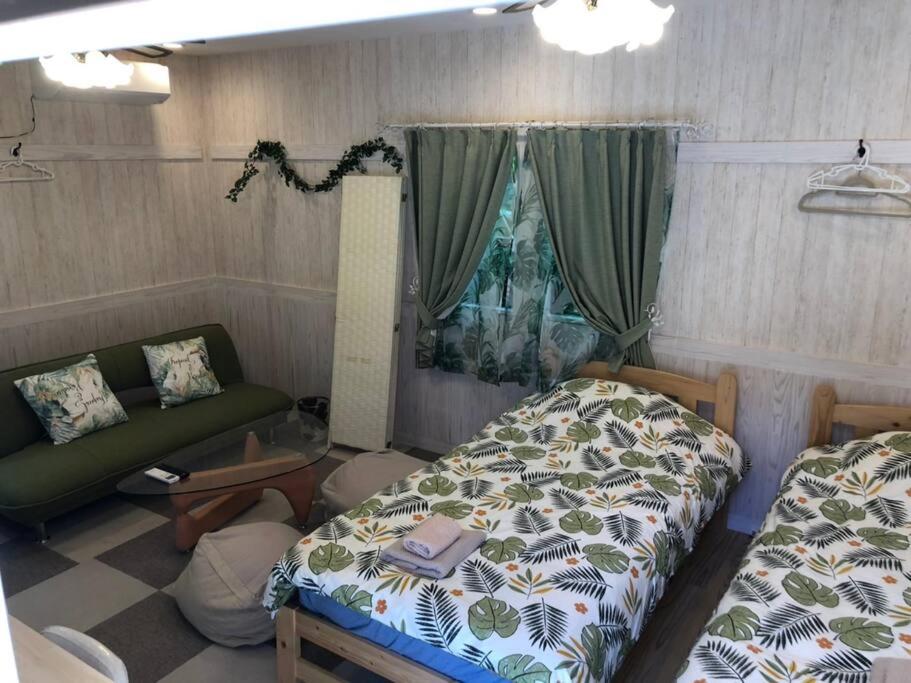 a room with two beds and a couch and a window at Chulashima Heartland in Onna