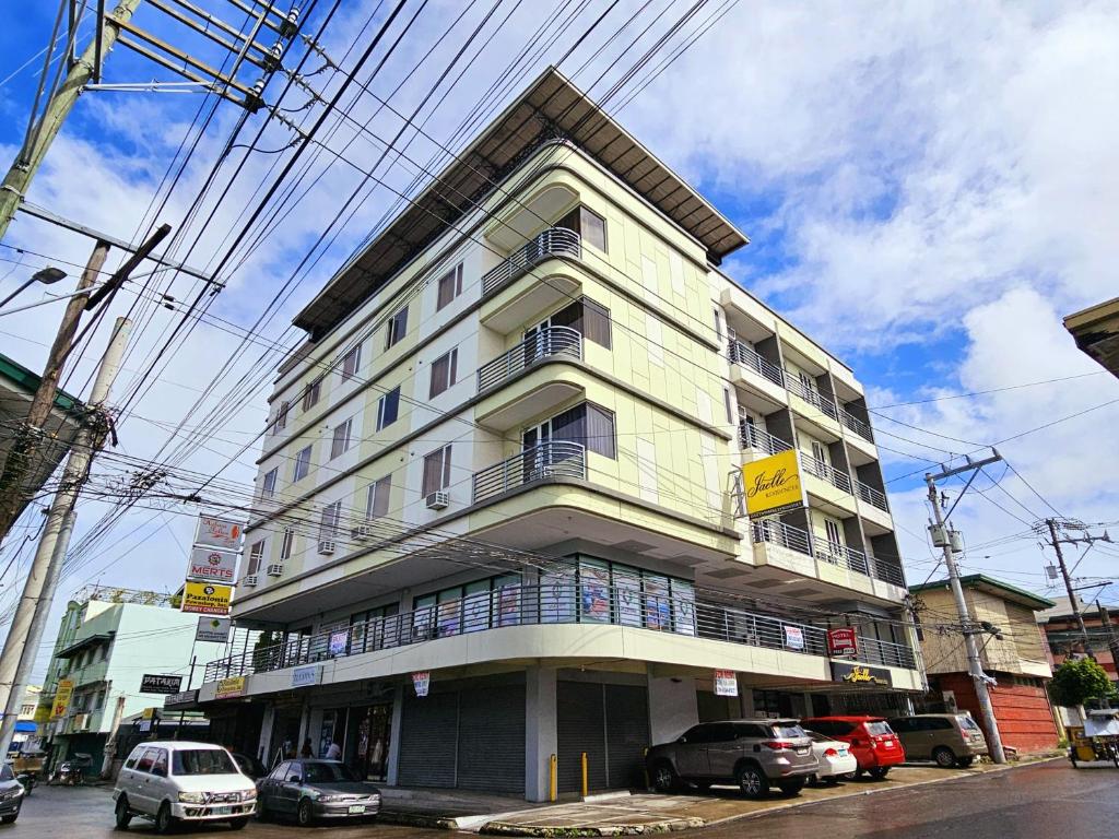 a tall building with cars parked in front of it at Jaelle Residences Hotel - Downtown in Lucena