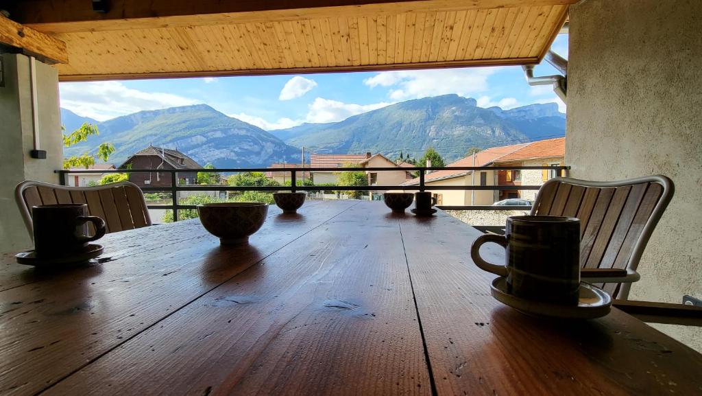 a wooden table with chairs and a view of mountains at 'Games of Home' - logement T3 in Saint-Égrève
