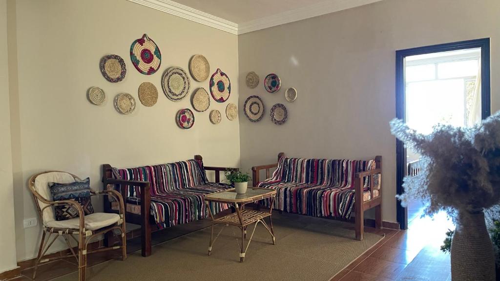 Sala de estar con 2 sofás, mesa y platos en la pared en La Casa Budget, en Marsa Alam