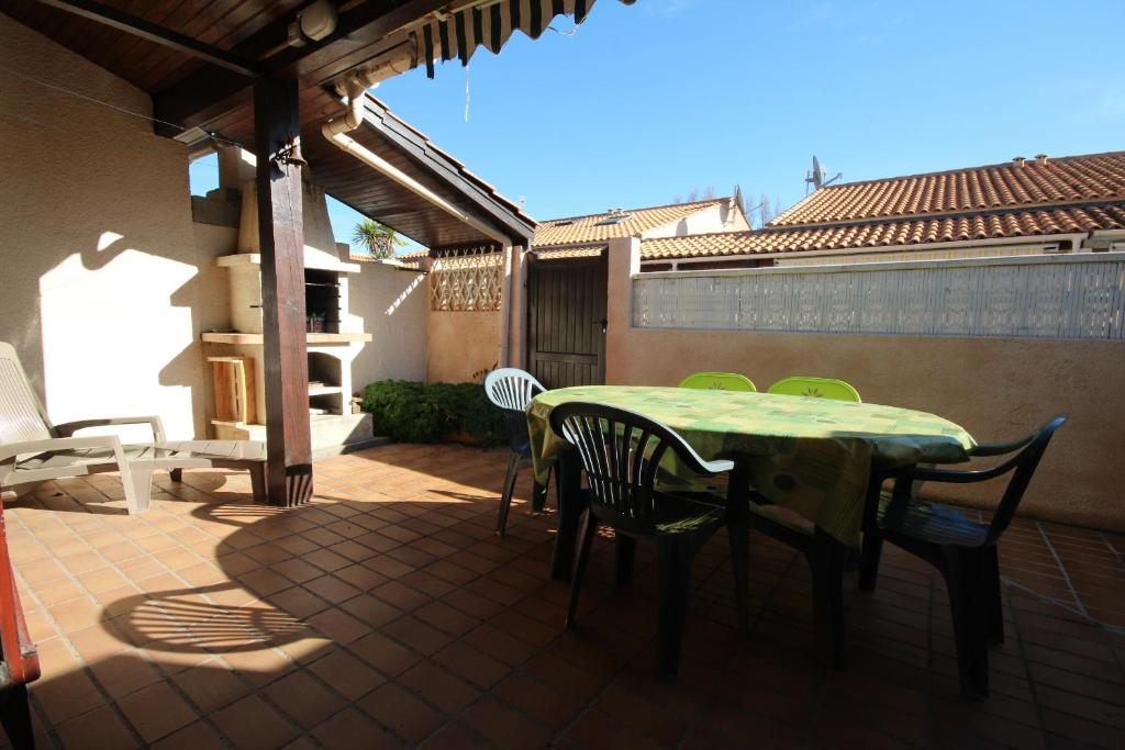 un patio avec une table et des chaises sur un patio dans l'établissement Villa 6 couchages 3 chambres terrasse ombragée parking dans résidence sécurisée piscine commune 400m de la mer LRJP93, à Portiragnes