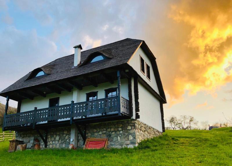a house with a balcony on top of a field at Casuta Bunicii, Bran in Bran