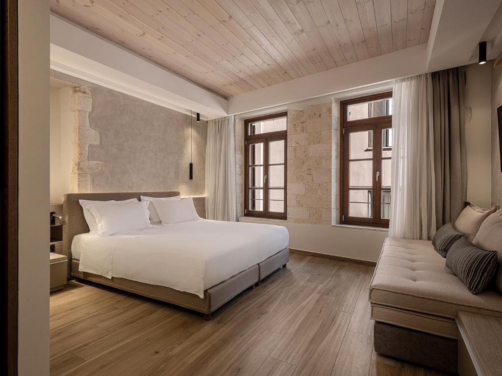 ein Schlafzimmer mit einem weißen Bett und einem Sofa in der Unterkunft CASA DORINI in Chania