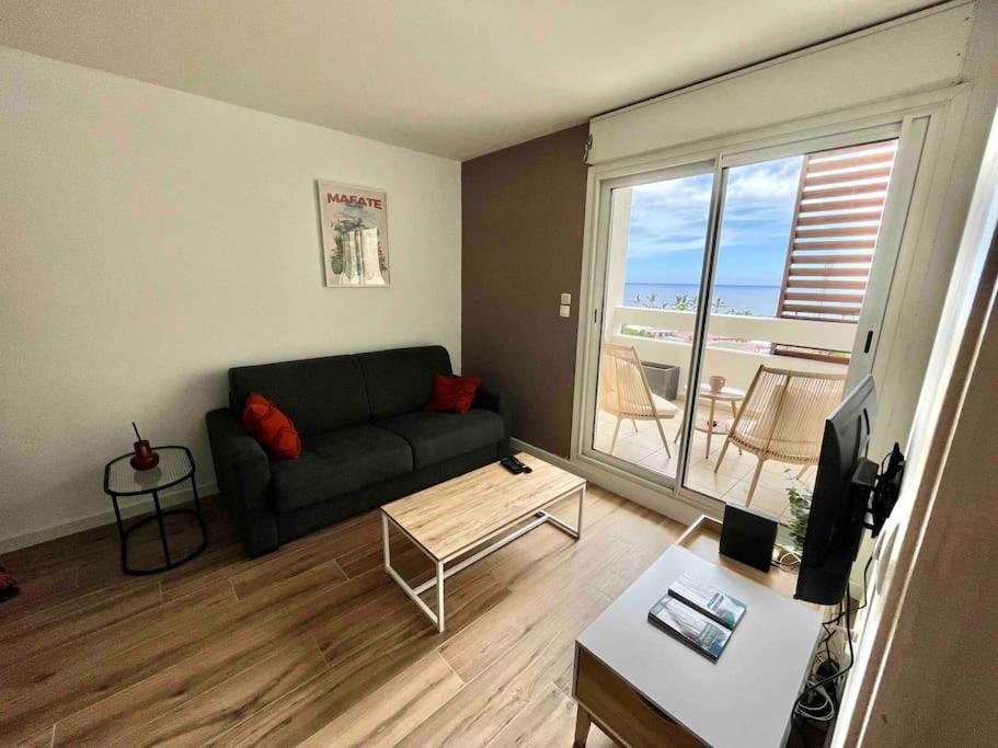 ein Wohnzimmer mit einem Sofa und einem Tisch in der Unterkunft Bel appartement vue mer - Mafat'appart in La Possession