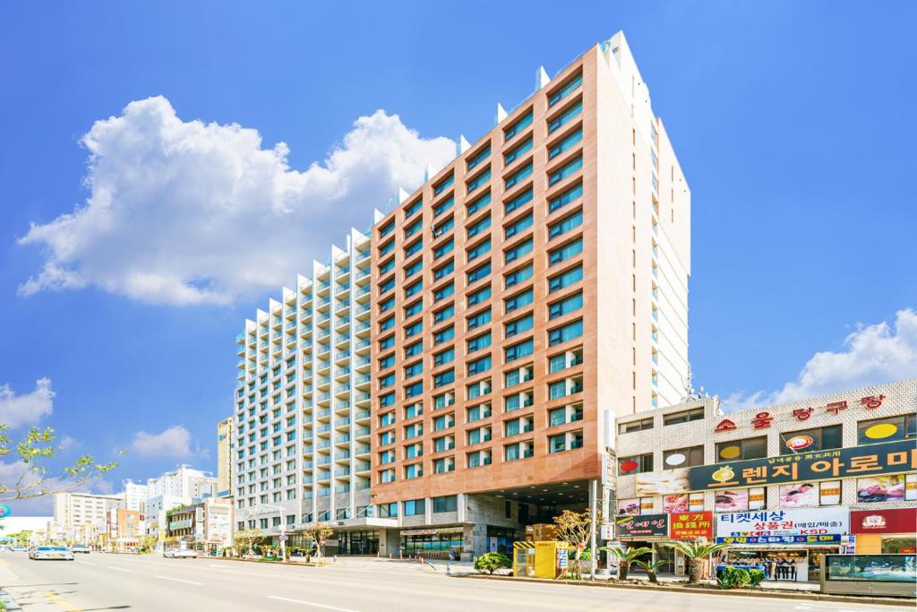 Un edificio alto sul lato di una strada di Hotel Air City Jeju a Jeju