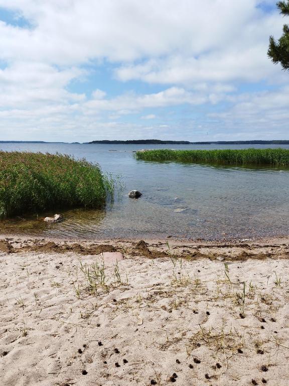 a beach with a body of water and some grass at Topsala MidIsland in Houtskari