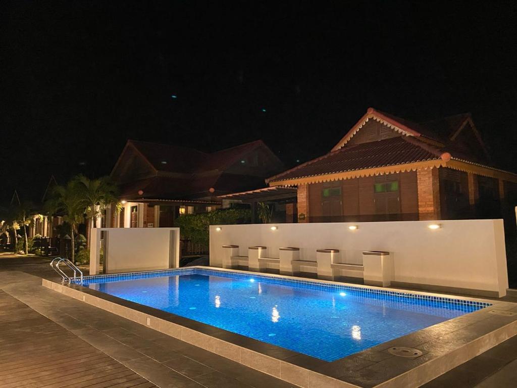 a swimming pool in front of a house at night at Jasmine Villa in Pantai Cenang