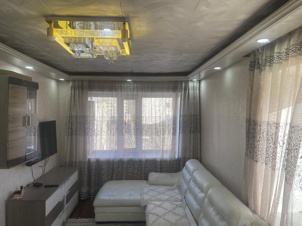 een woonkamer met een witte bank en een televisie bij Fully furnished 1 room apt in Ulaanbaatar