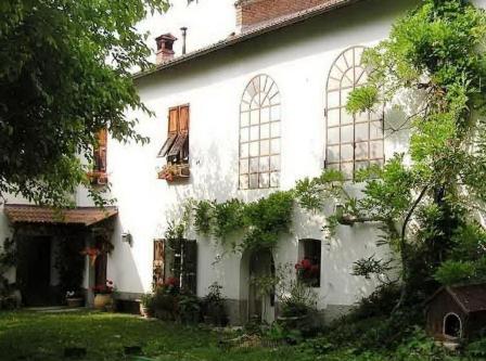 un edificio bianco con finestre e piante sopra di Bed & Breakfast Cascina Cin Cin a Novi Ligure