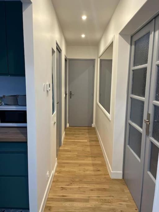 un couloir menant à une cuisine avec des armoires bleues dans l&#39;établissement appartement cosy 6 pers, à Noisy-le-Sec