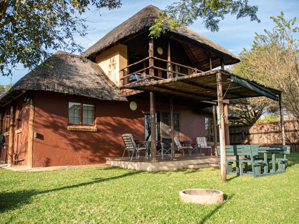 una casa con techo de paja y sillas en el patio en Wild and Water Dinokeng en Dinokeng Game Reserve