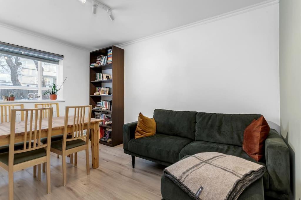 ein Wohnzimmer mit einem grünen Sofa und einem Tisch in der Unterkunft Bright 1BR Apartment in Reykjavík in Reykjavík