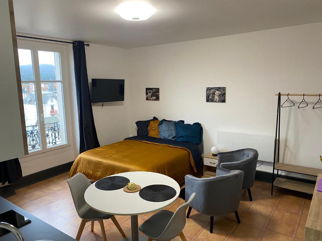 une chambre avec un lit, une table et des chaises dans l'établissement Studio Yannick, à Vittel