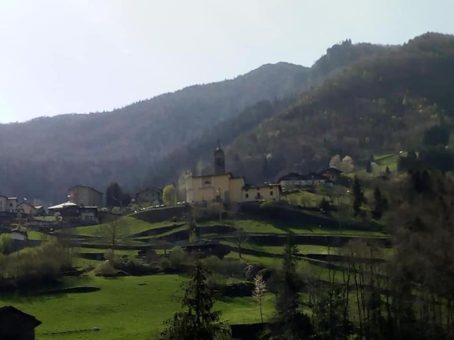 een dorp in een veld met een berg op de achtergrond bij Vista panoramica - Chalet rustico in montagna in Valgoglio