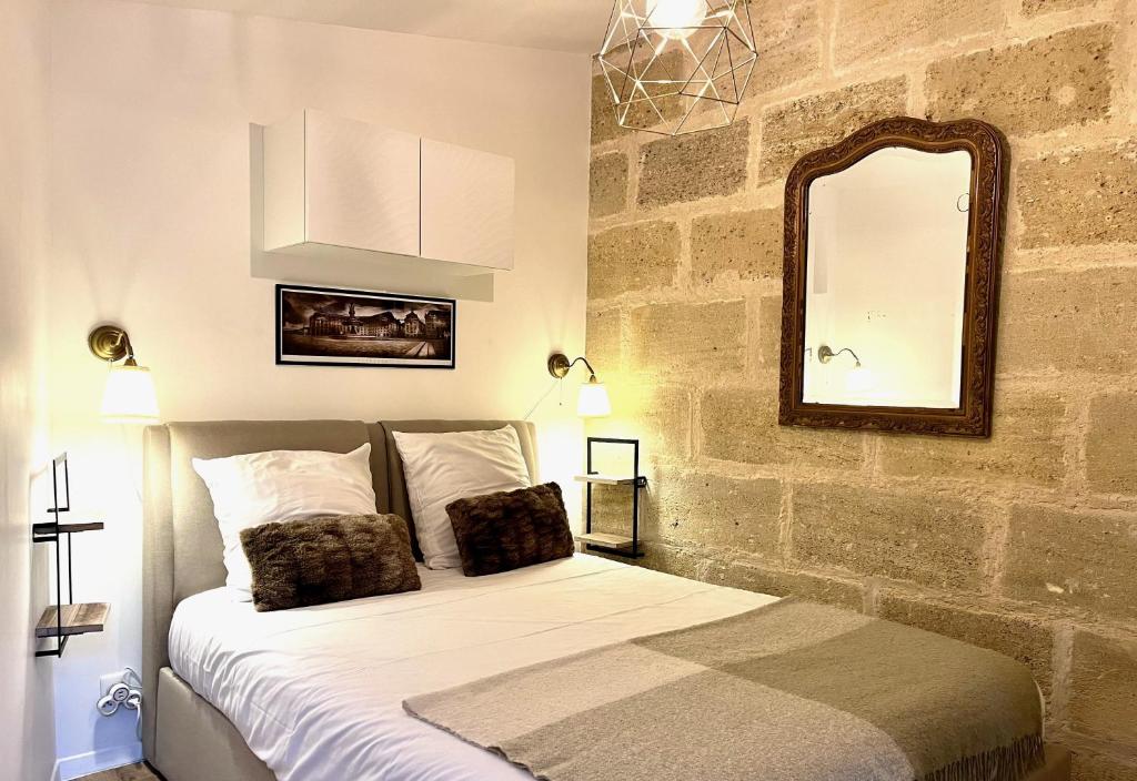 a bedroom with a bed with a mirror on the wall at Les Suites d'Aliénor, Suite Cosy in Pessac