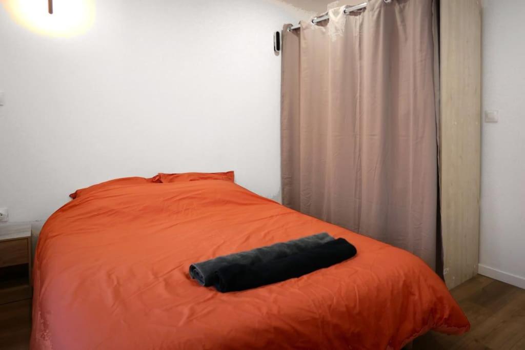 uma grande cama laranja com uma almofada preta em L’Impérial 4- CentreVille- WIFI em Étampes