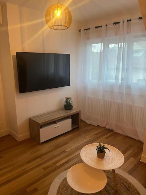 un salon avec une télévision à écran plat et une table dans l'établissement agréable, à Noisy-le-Sec