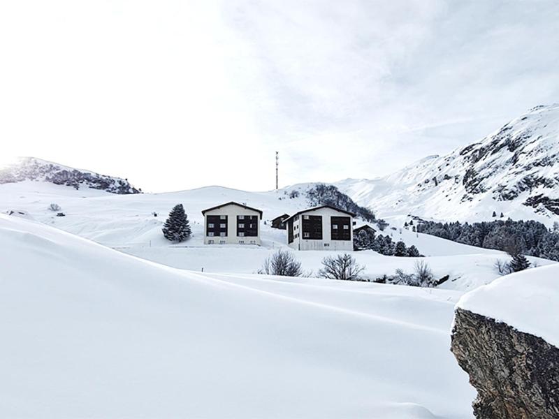 a house in the snow with mountains in the background at Casa Bivio in Bivio