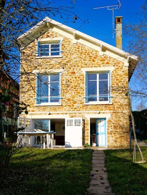 une maison en briques avec une porte blanche sur une pelouse dans l'établissement la charmante maison d'antan, à Thorigny-sur-Marne