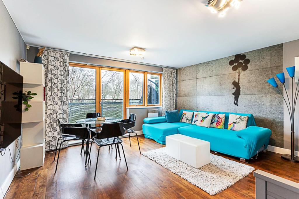 a living room with a blue couch and a table at Modern 2-Bed Flat Bethnal Green in London
