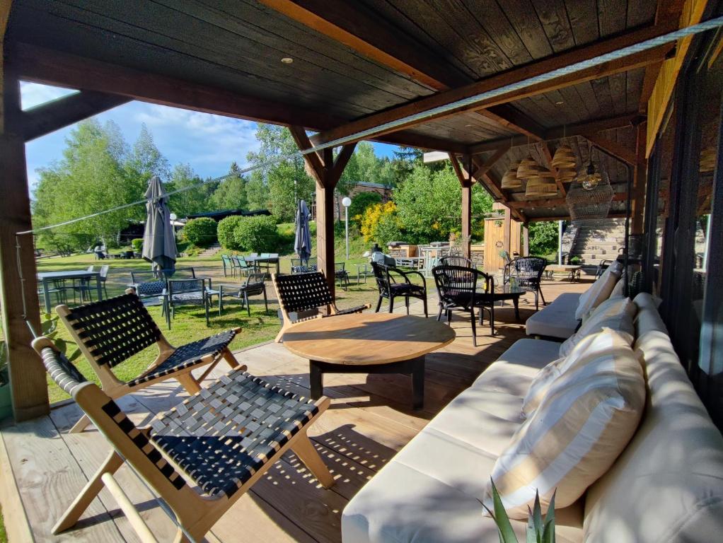 a patio with chairs and a couch and a table at Les Chalets Du Goulet in Le Bleymard
