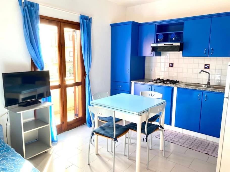 a kitchen with blue cabinets and a blue table and chairs at Appartamento Lucca 2 in San Teodoro