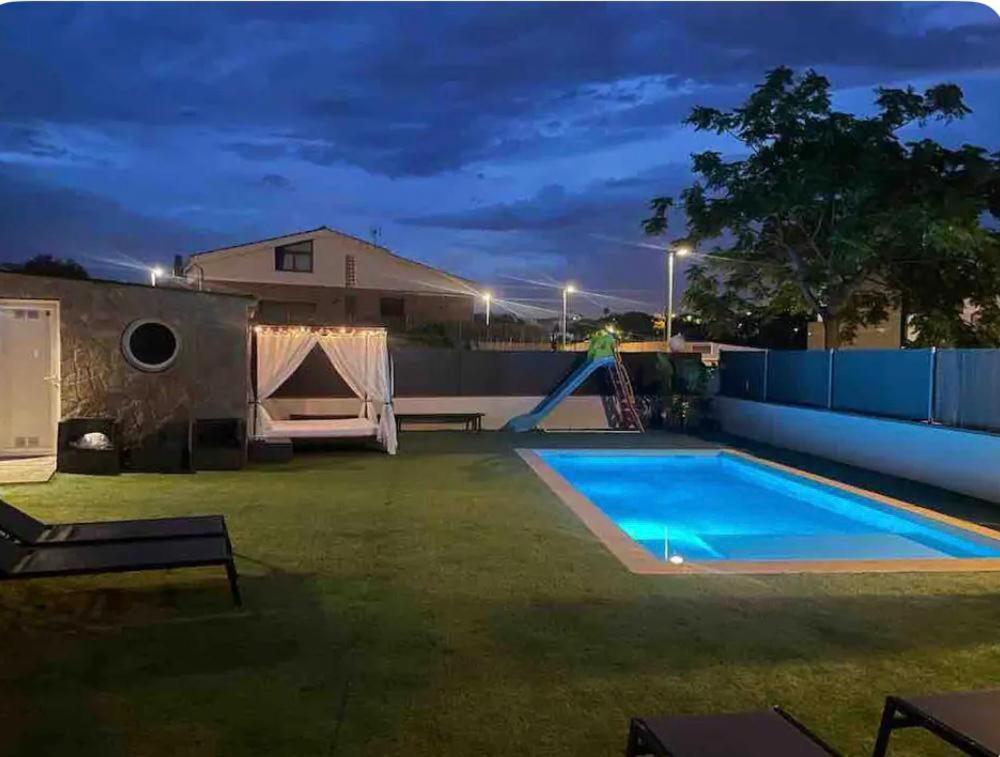 a backyard with a swimming pool at night at Acogedora casa con piscina y 3 dormitorios in Vilanova i la Geltrú