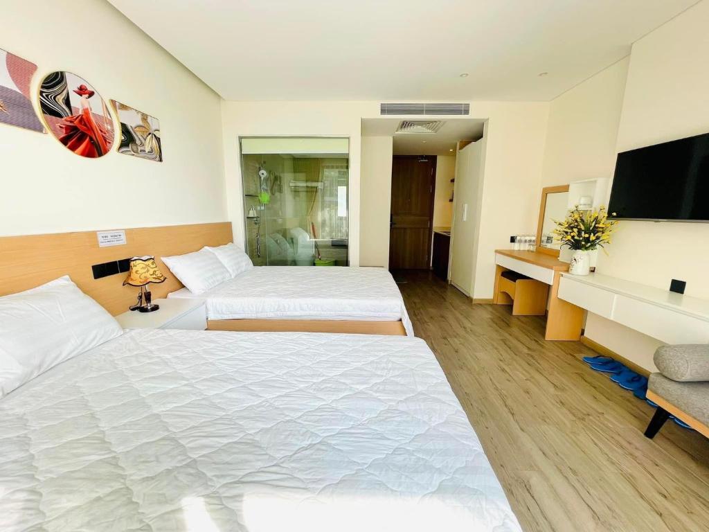 Cette chambre comprend 2 lits et une télévision à écran plat. dans l'établissement Căn hộ nghỉ dưỡng 5 sao APEC MANDALA PHÚ YÊN, à Liên Trì (3)