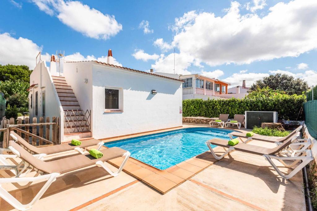 a swimming pool with two chairs and a house at Villa Tia Dora in Cala en Blanes