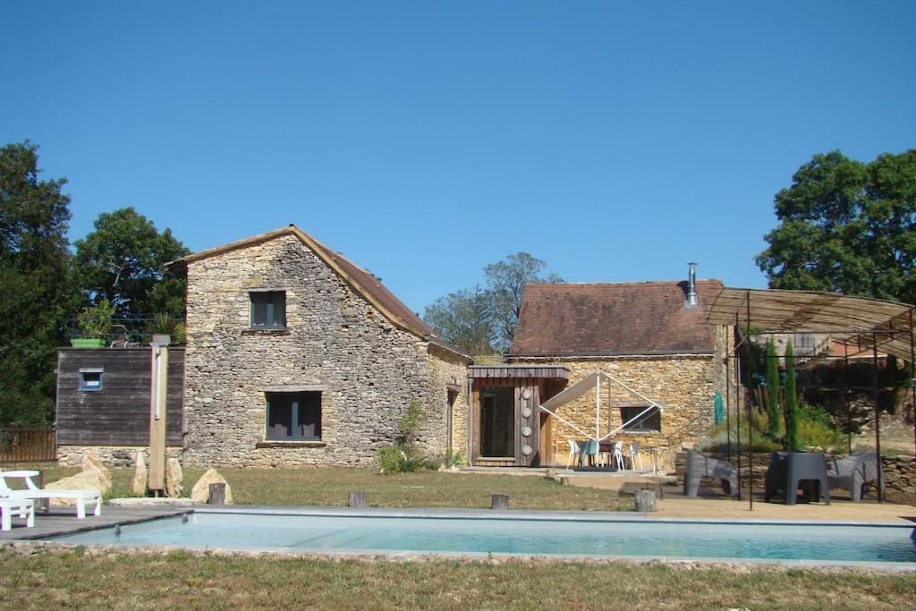una antigua casa de piedra con una piscina frente a ella en Gîte Les Grangettes*Piscine*Cadre bucolique, en Campagnac-lès-Quercy
