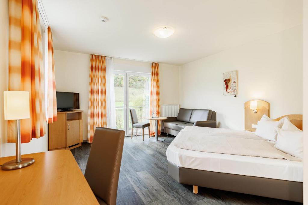 ein Hotelzimmer mit einem Bett und einem Wohnzimmer in der Unterkunft Hotel Restaurant Talblick in Bad Ditzenbach