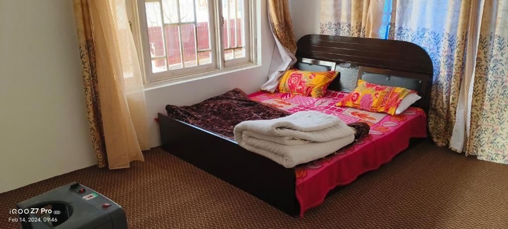 ein kleines Schlafzimmer mit einem Bett mit Decken und Kissen in der Unterkunft MAGRAY GUEST HOUSE in Tangmarg