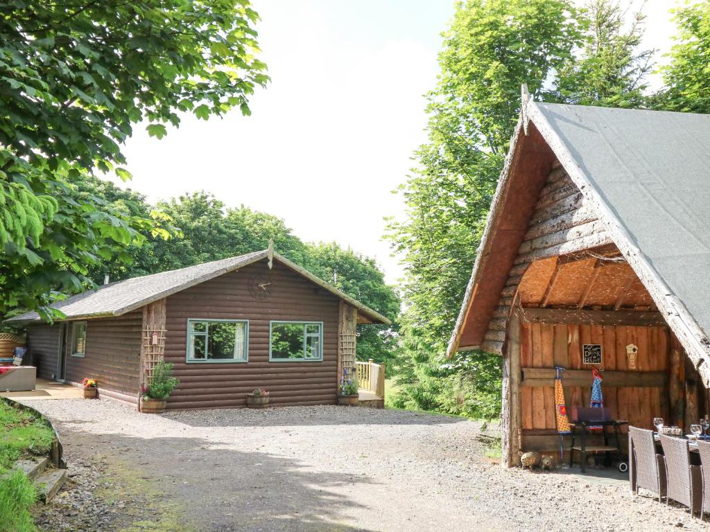een kleine houten hut naast een huis bij Pond Farm Woodlands in Ugthorpe