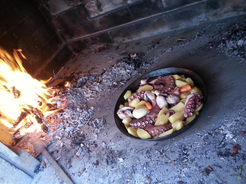 a pan filled with food next to a fire at Apartment Tara in Sumartin