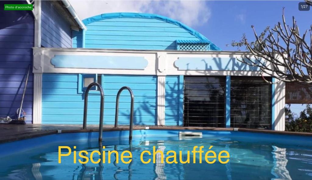 een zwembad voor een huis met een blauwe garage bij La maison des artistes in Saint-Leu