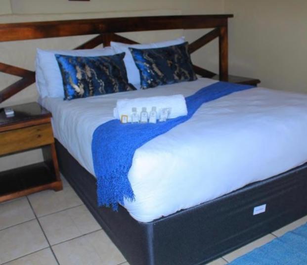 1 dormitorio con 1 cama con sábanas azules y blancas en Butterfly tree suites, en Phalaborwa
