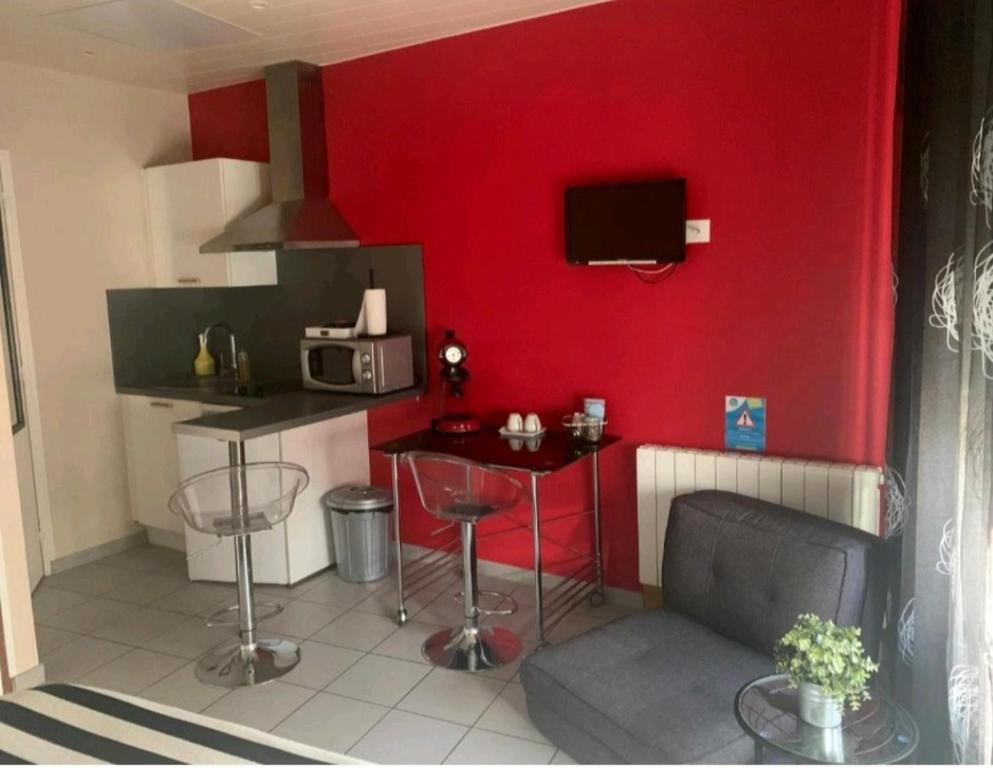 a kitchen with a red wall with a table and a microwave at Escal Evasion in Auzances
