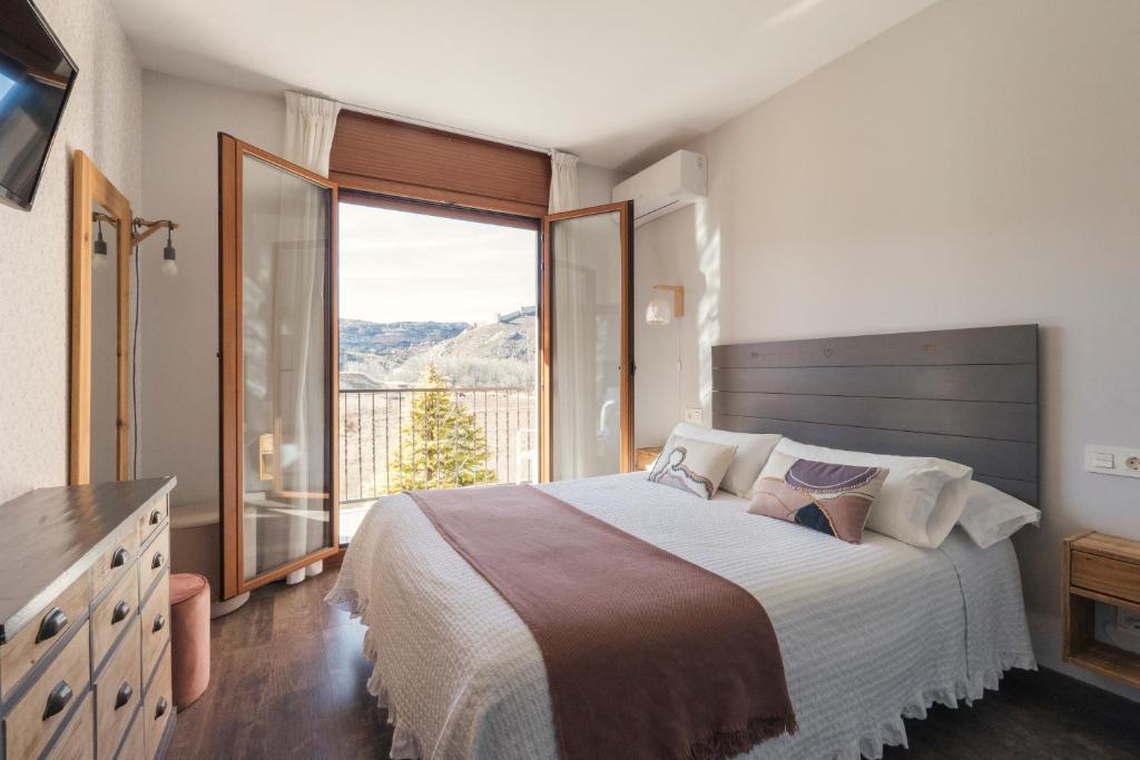 a bedroom with a large bed and a large window at Hotel Casa Cauma in Albarracín