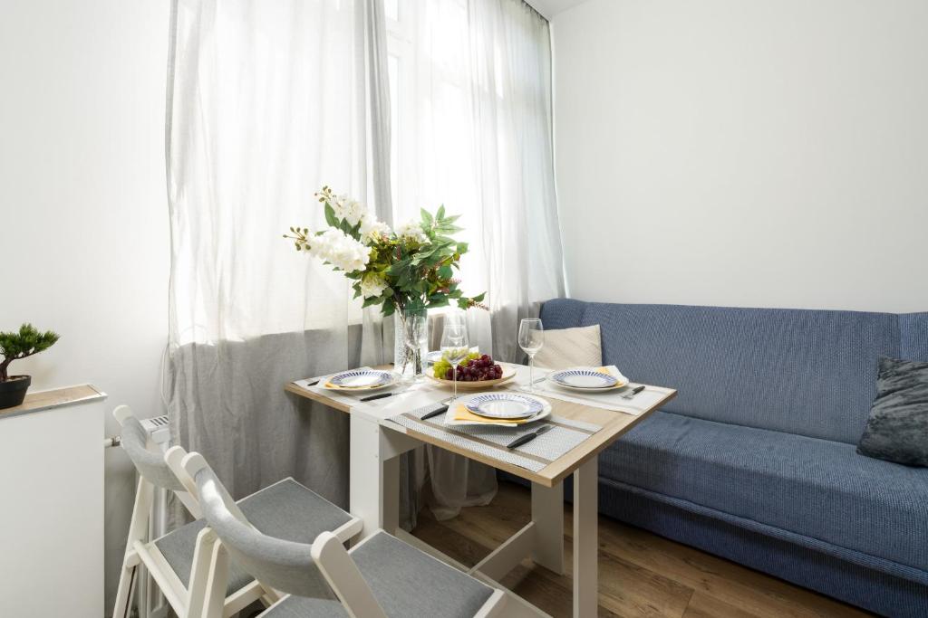 a living room with a table and a blue couch at Czeremchowa Apartment in Poznan by Renters in Poznań