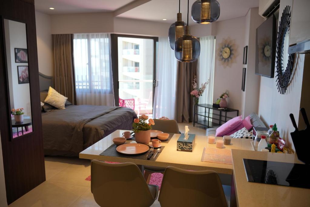 Dominiks Modern pink Studio Balcony & Ocean View Balcony 11 Floor Fast-Wifi at Tambuli Resort في Maribago: غرفة معيشة مع سرير وطاولة في غرفة