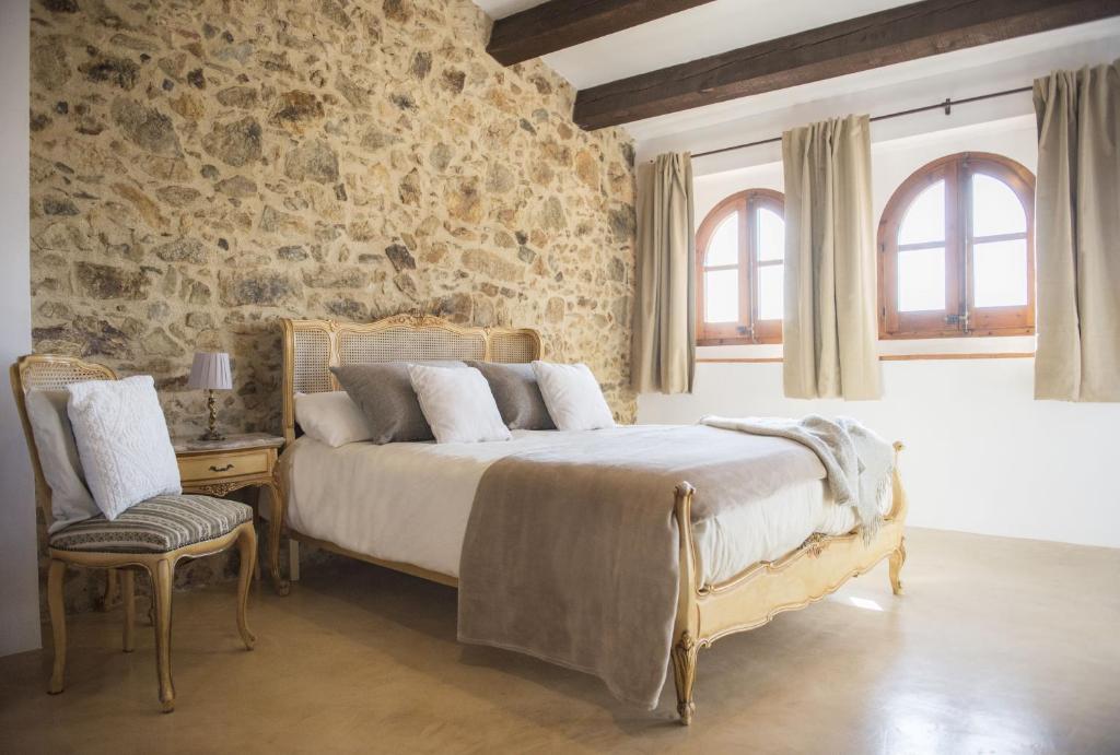 - une chambre avec un lit et un mur en pierre dans l'établissement Casa Baraldës, à Vilajuiga