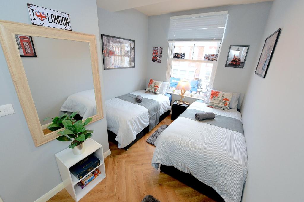 um quarto com 2 camas e um espelho em 2 BEDROOM FLAT in WOOD GREEN PICCADILLY LINE em Londres