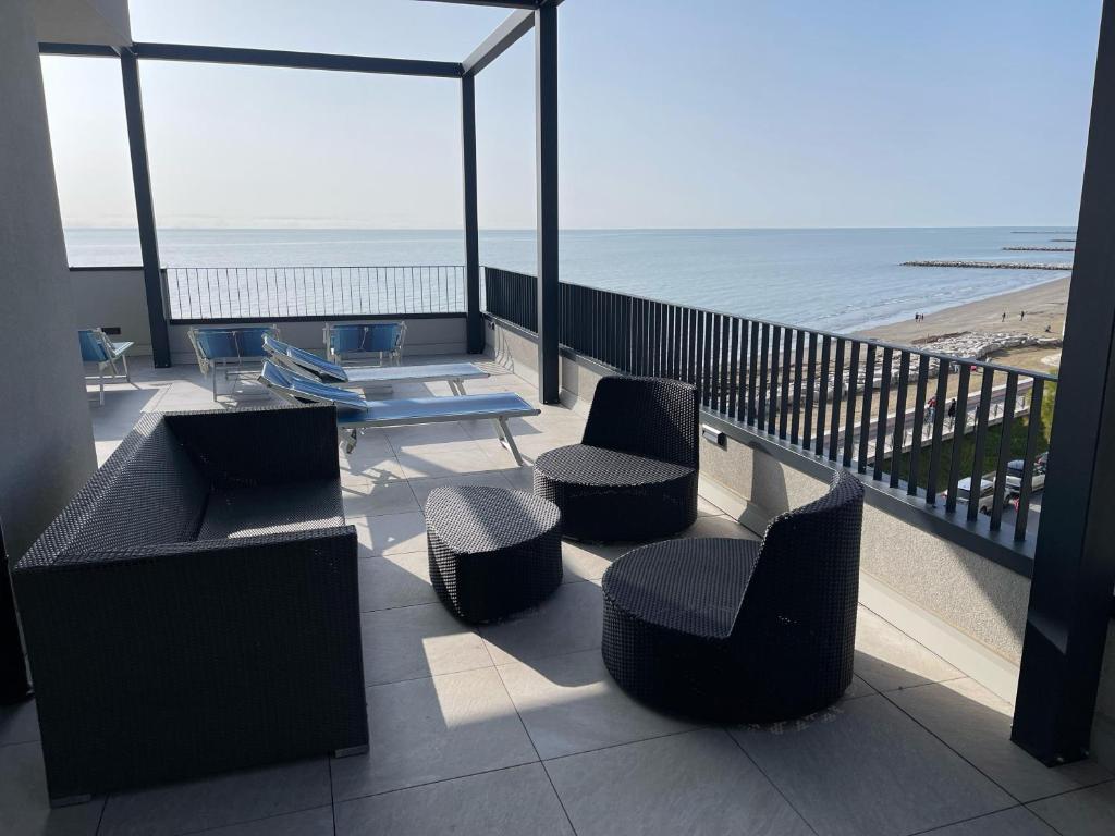 a balcony with chairs and a table and the beach at Nuovo Residence Serenissima Frontemare - Agenzia Cocal in Caorle