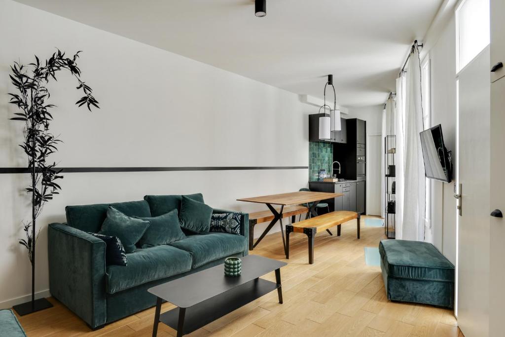 a living room with a green couch and a table at 124 Suite Beata - Superbe Appartement à Paris in Paris