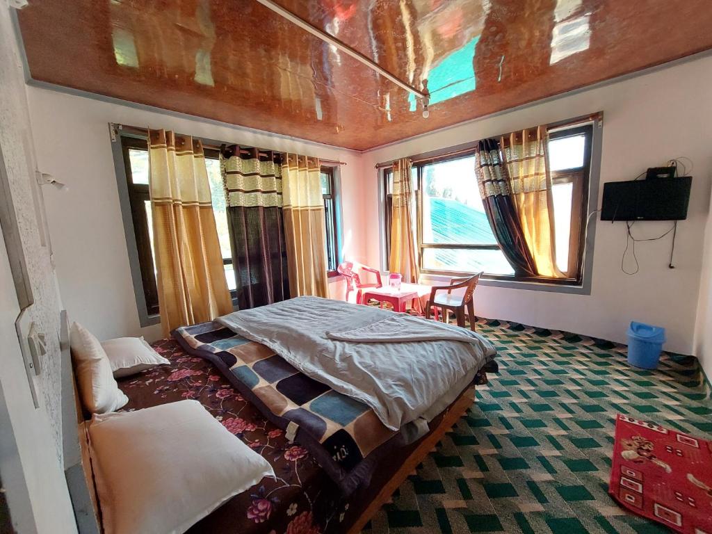 a bedroom with a bed in a room with windows at Forest inn pahalgam in Anantnāg