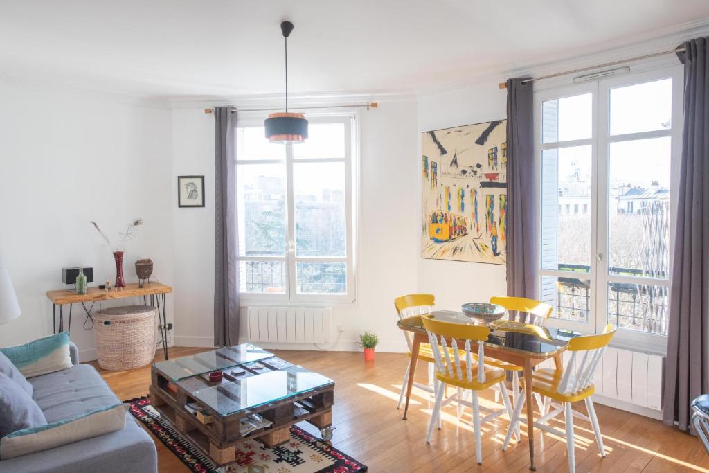 uma sala de estar com mesa e cadeiras em Cosy and very nice flat with open view on a parc em Paris