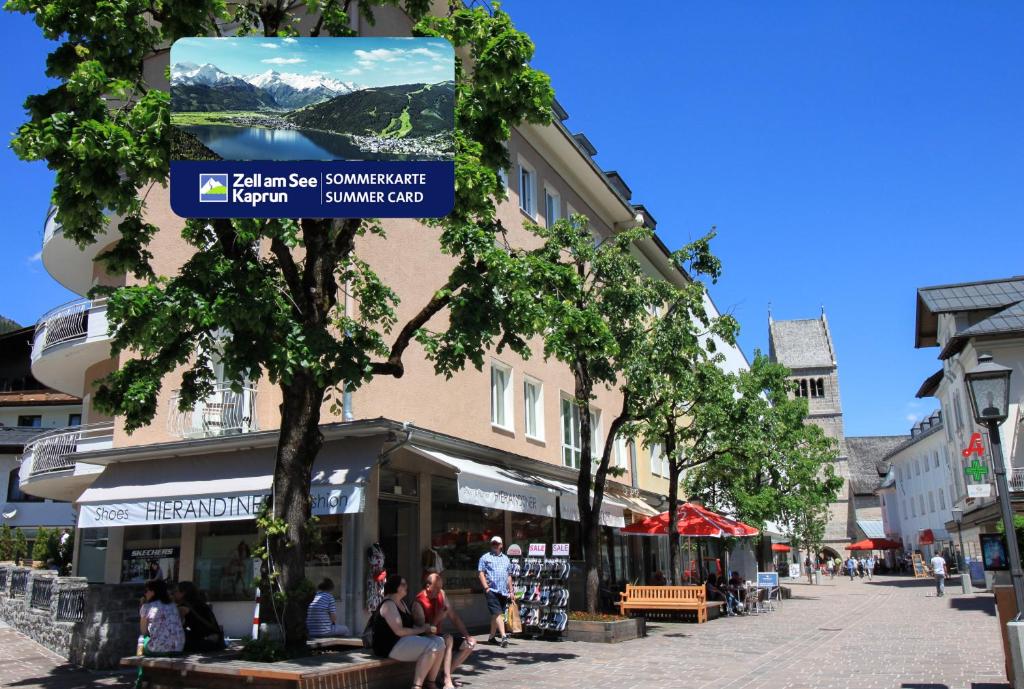 a street with people sitting on benches in front of a building at Living Eden by we rent, SUMMERCARD INCLUDED in Zell am See