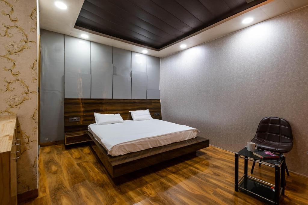 een slaapkamer met een bed en een stoel erin bij FabHotel Le Masrana Inn in Mussoorie